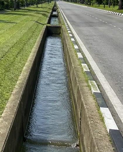 Saluran longkang di tepi jalan utama, air mengalir lancar